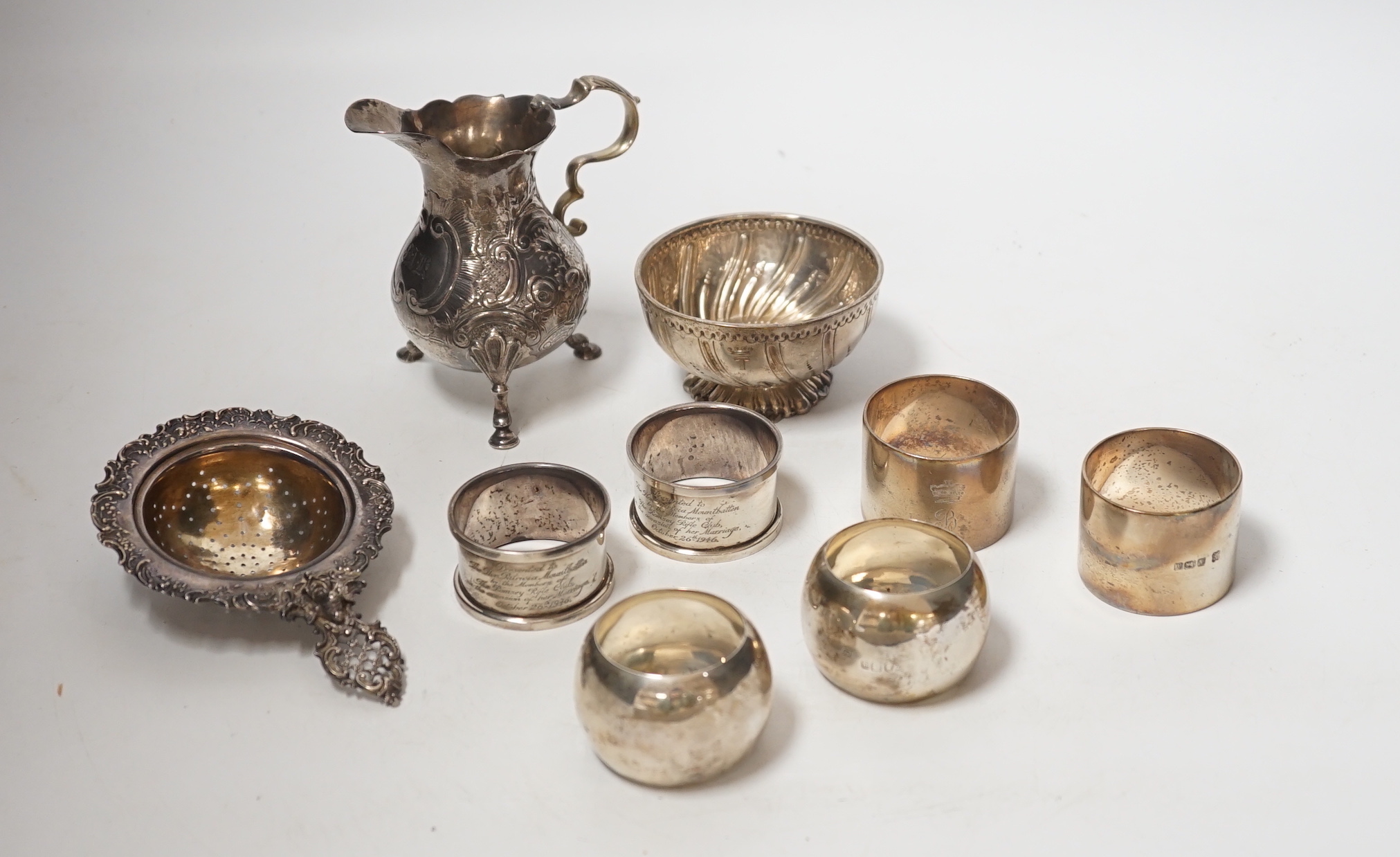 Sundry silver including six silver napkin rings, an 800 standard tea strainer and a white metal bowl and cream jug.